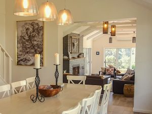 Riverlea Retreat Mudgee Dining and Lounge with lit up candle and beautiful hanging ceiling lights over a white dinning table and chairs.