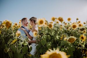 A newly married couple embracing eye to eye in sunflower field. Photo taken by Stephanie Halpin photographer